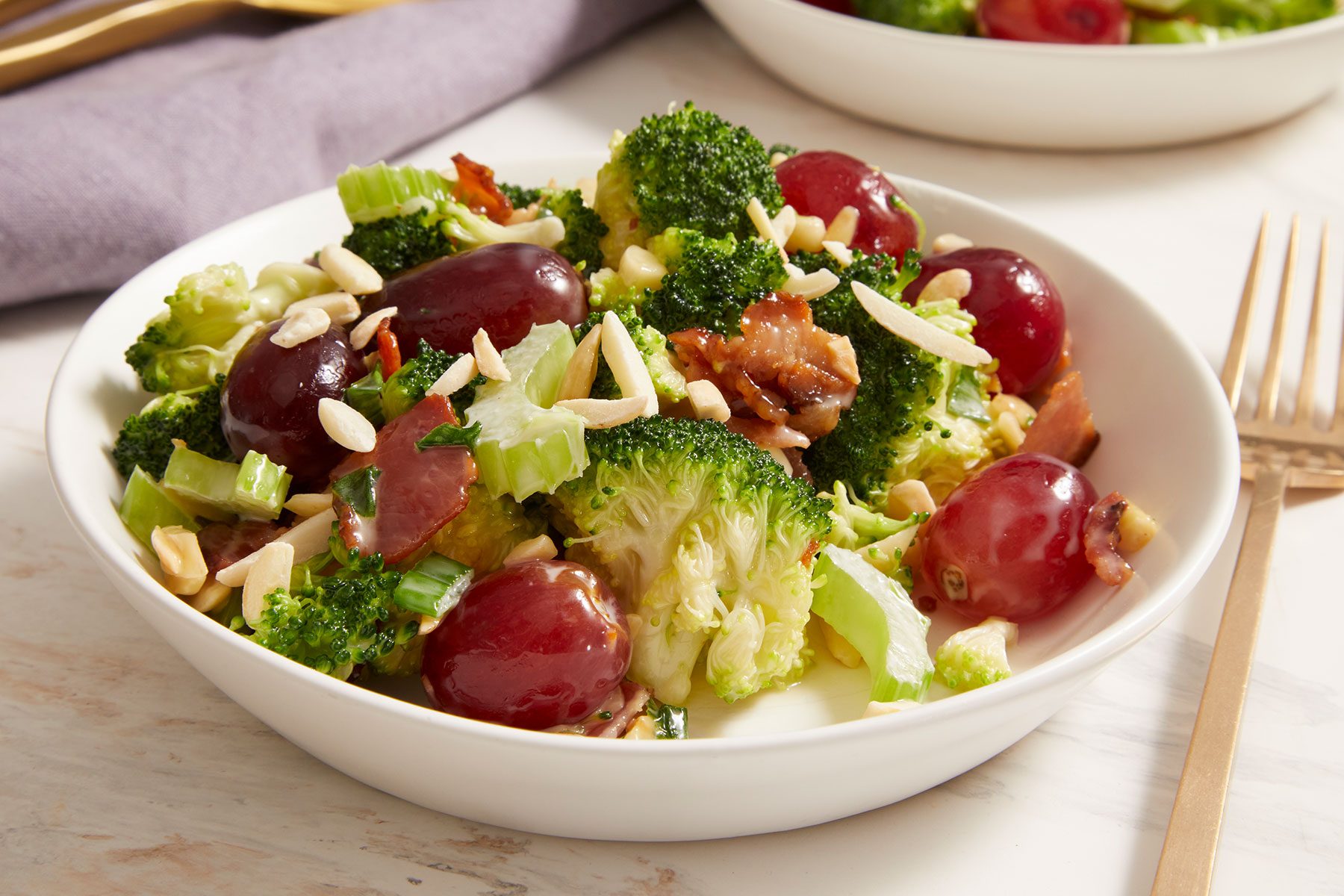 Broccoli Grape Salad in a white bowl with a fork placed on side.