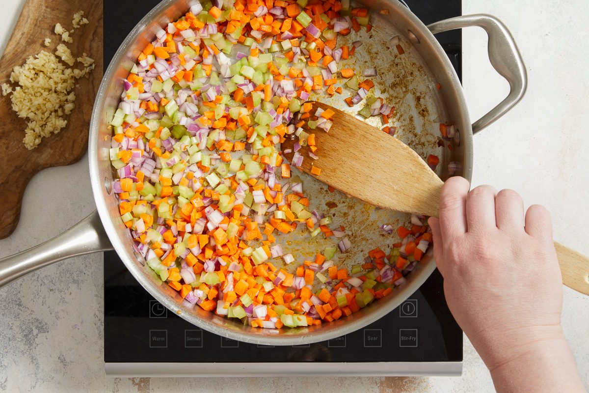 carrots, celery and onion being sautéed in a large skillet