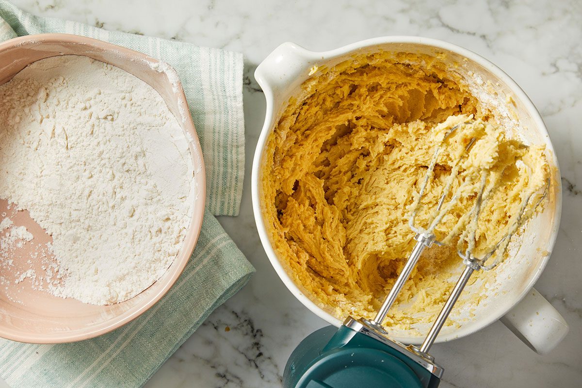 Overhead horizontal image of cookie dough being mixed with flour and wet ingredients in a mixing bowl.