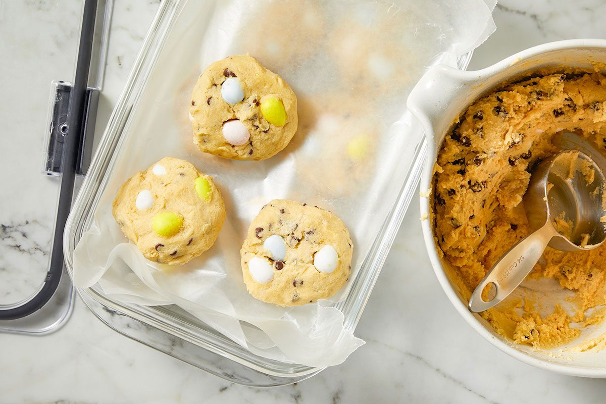 Overhead horizontal image of scooped cookie dough balls with candy pieces placed into a baking dish.