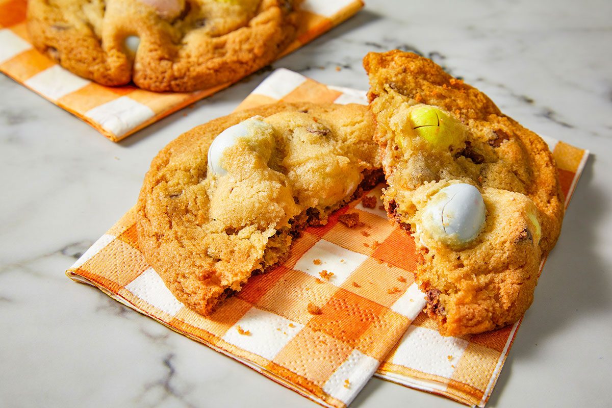Eye-level horizontal image of a broken Cadbury egg cookie showing soft interior and melted candy center.
