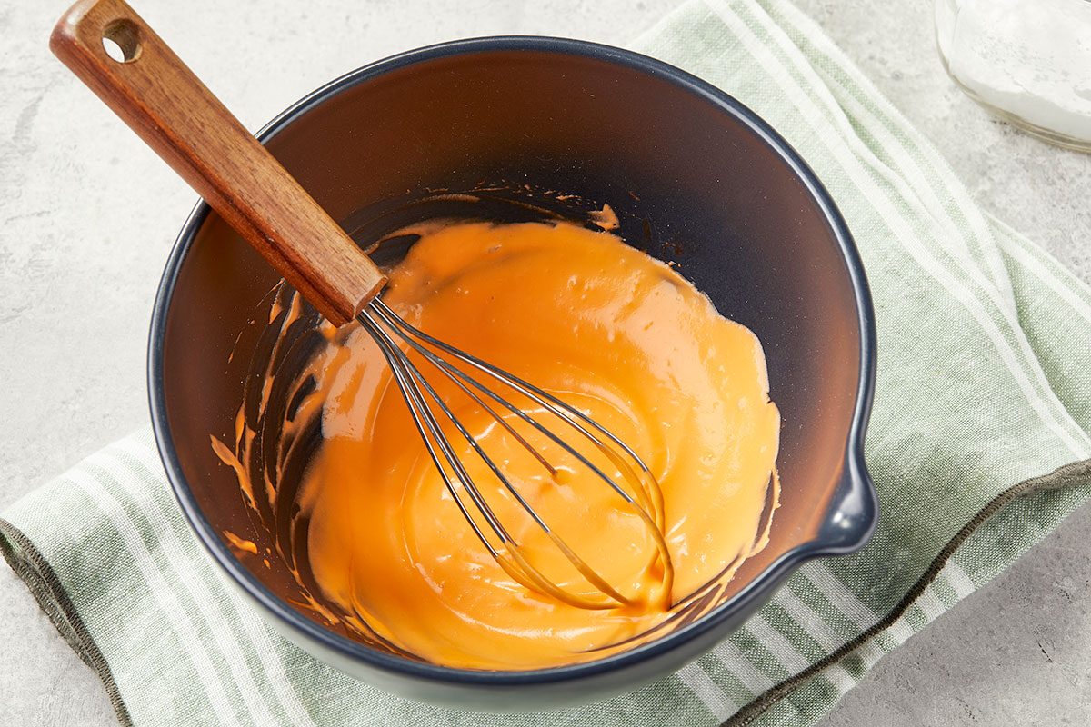 Overhead image of carrot cream being whisked in a bowl to create the creamy topping for a Carrot Cake White Russian cocktail.