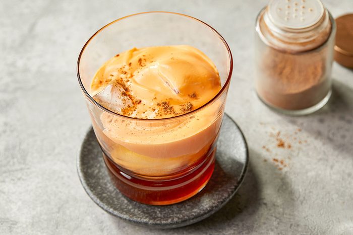 Overhead image of Carrot Cake White Russian cocktail served in a glass with creamy carrot topping and sprinkled cinnamon.