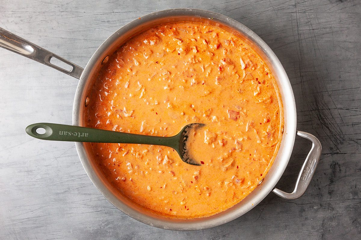 Overhead view of creamy vodka sauce simmering in a skillet after being blended with tomatoes and heavy cream. The smooth orange sauce fills the pan as it thickens during cooking.