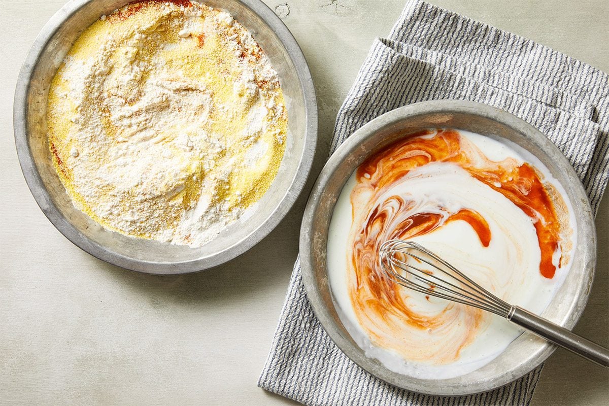 Overhead shot of two small bowls of sauce with hot sauce swirled in for flavoring on a light napkin.