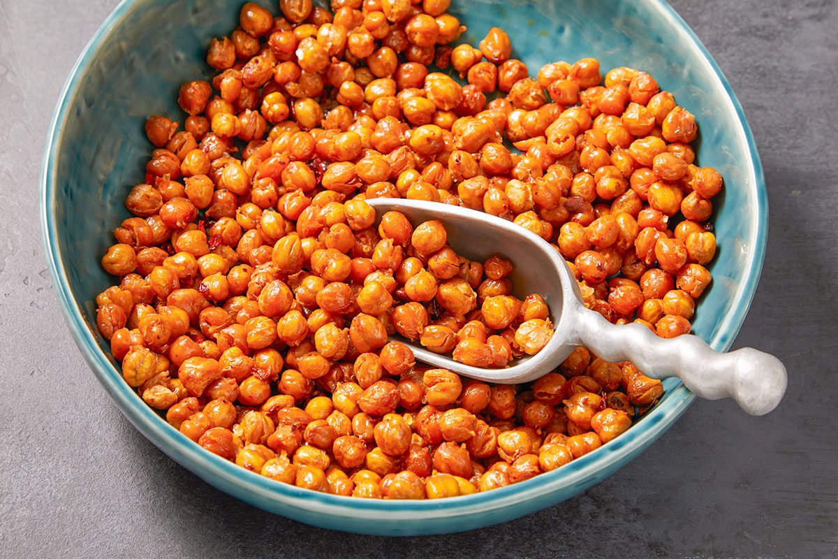 Overhead horizontal close-up of chili crisp chickpeas in a bowl with serving spoon.