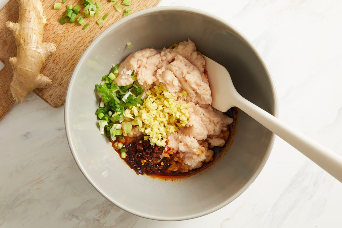 ground chicken, minced green onions, soy sauce, minced gingerroot, chili crisp and sesame oil mixed in a bowl