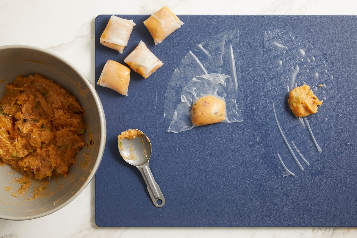 filling being wrapped in rice paper on a cutting board