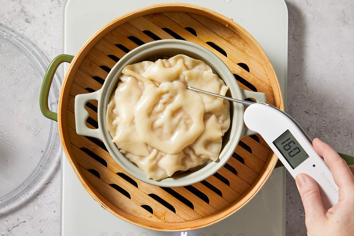 Overhead shot of the dumpling lasagna cooking in a steamer basket with wonton wrappers forming the top layer as the dish cooks.