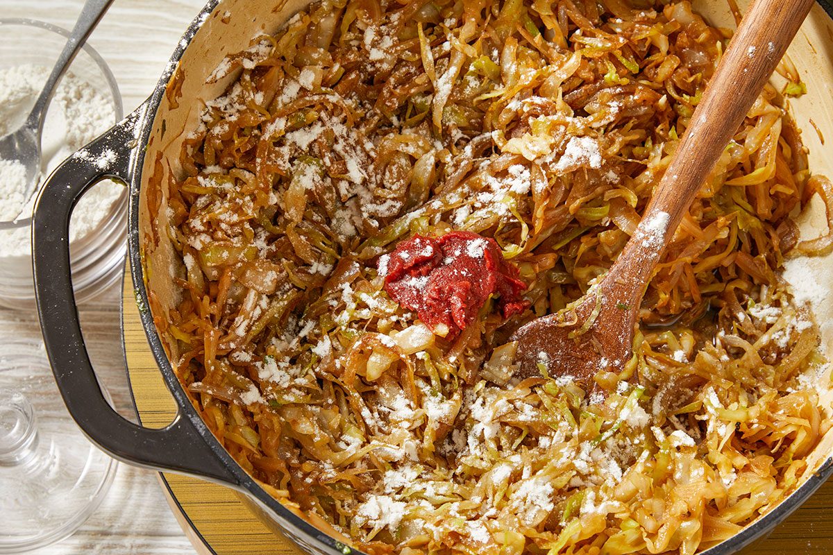 Overhead horizontal image of caramelized cabbage and onions with tomato paste and seasonings in a Dutch oven.
