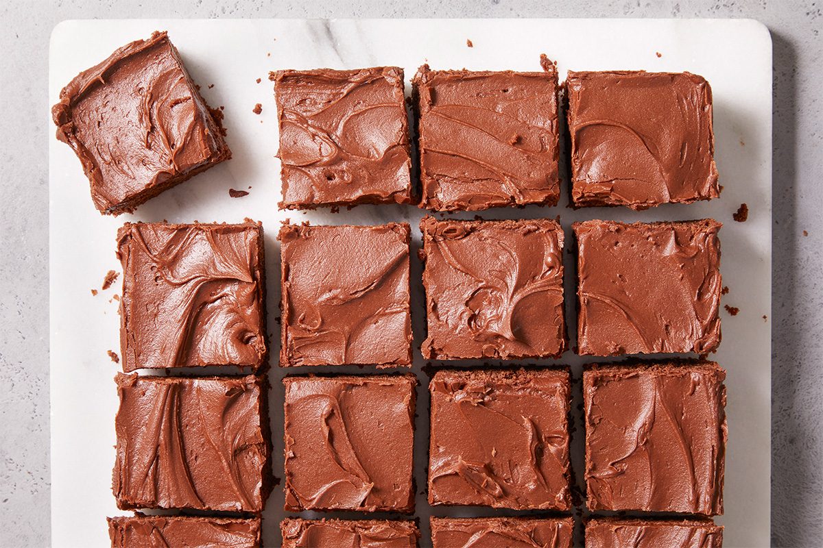 Overhead horizontal push and pulls image of Frosted Fudge Brownies cut into even squares in a grid pattern, showcasing glossy chocolate frosting and clean slice lines.