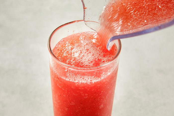 Close-up action shot of a frozen strawberry daiquiri being poured from a blender into a tall glass