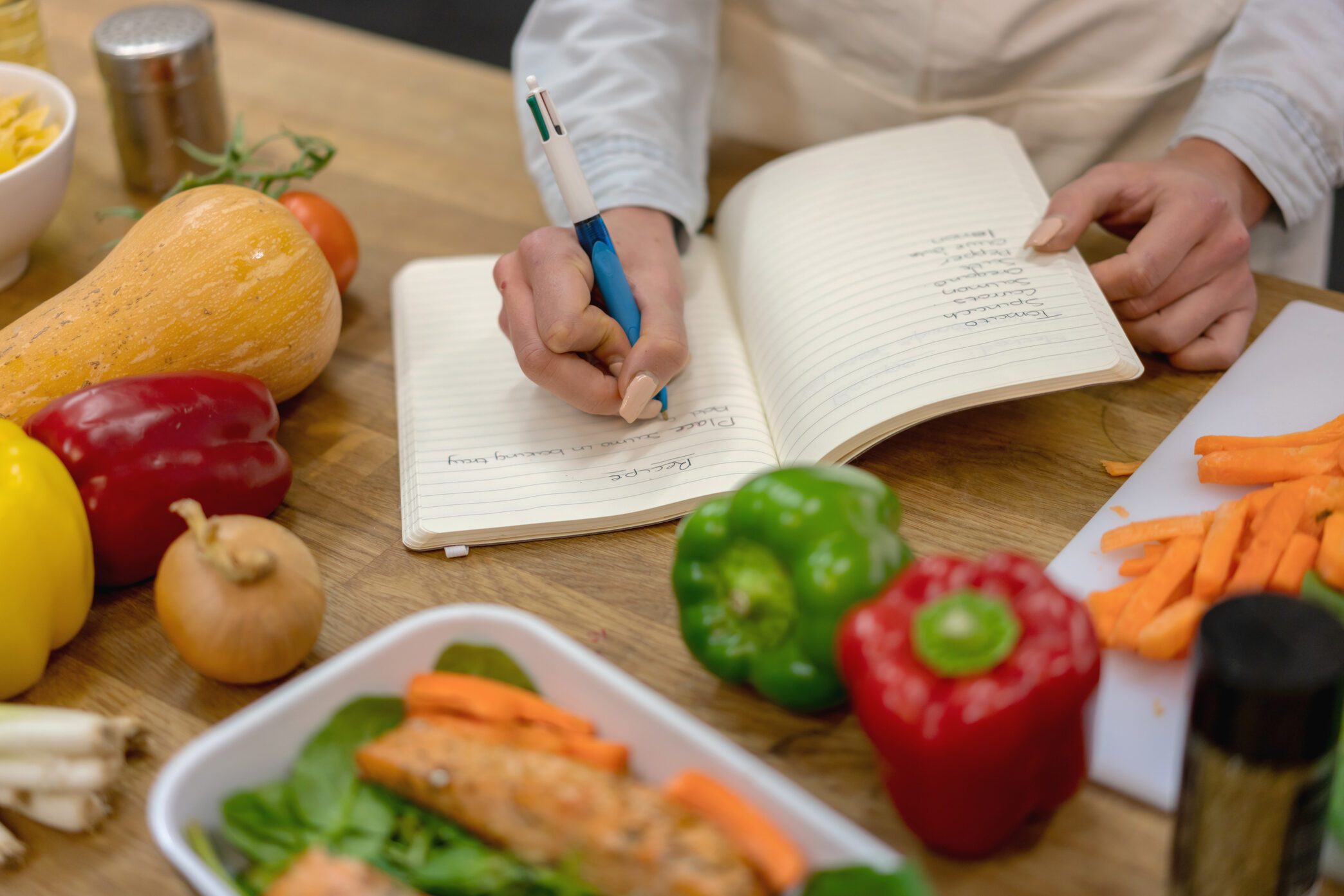 Woman at home writing a vegetarian recipe while cooking