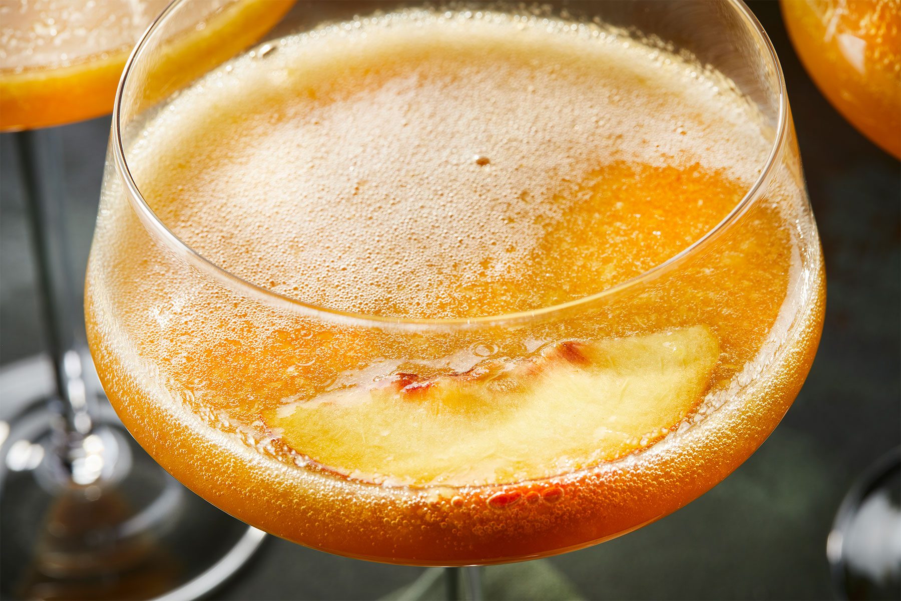 Hot Honey Peach Bellini closeup with a slice of peach