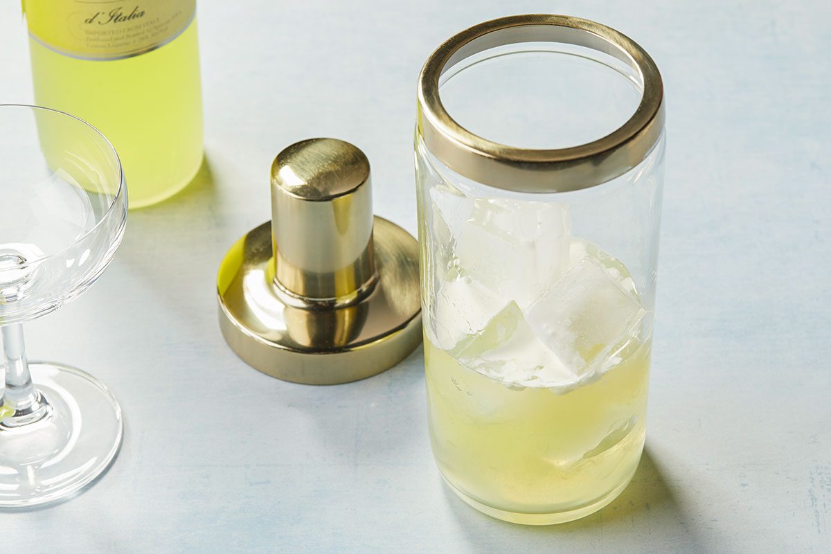 Overhead image showing cocktail ingredients including limoncello, ice and a cocktail shaker being prepared to make a Lemon Cream Martini.