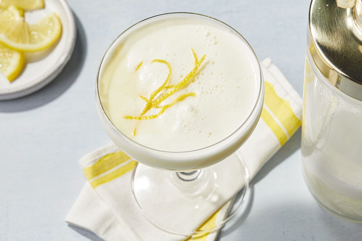 Overhead image of a finished Lemon Cream Martini with creamy foam and lemon zest garnish served in a coupe glass.