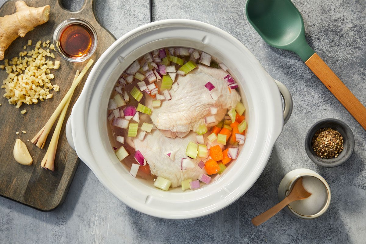 RMS 281394 Modern Slow Cooker Lemongrass Ginger Chicken Noodle Soup; How to; Step 1; Slow cooker with water; chicken; carrot; celery; onion; lemongrass; Edge in ginger; garlic; fish sauce; salt; and pepper