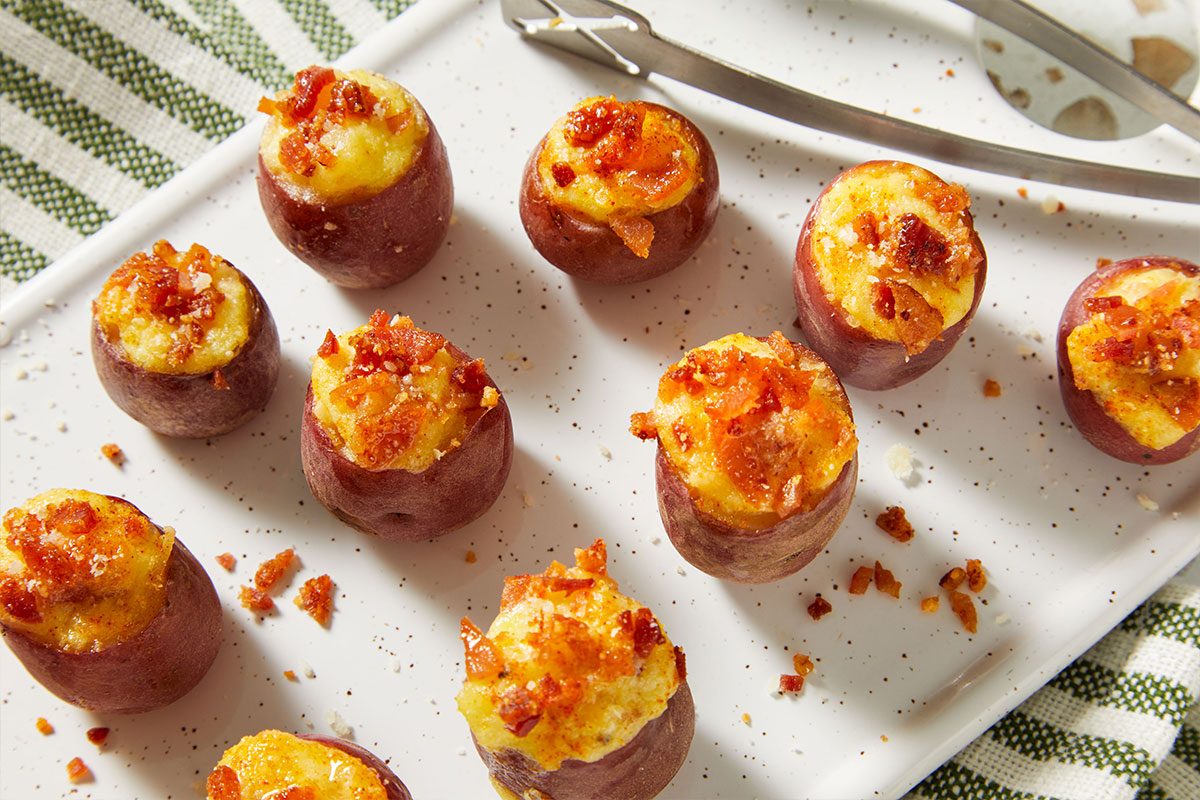 Overhead shot of Stuffed Baby Red Potatoes arranged on a platter, topped with melted cheese and garnished with herbs.