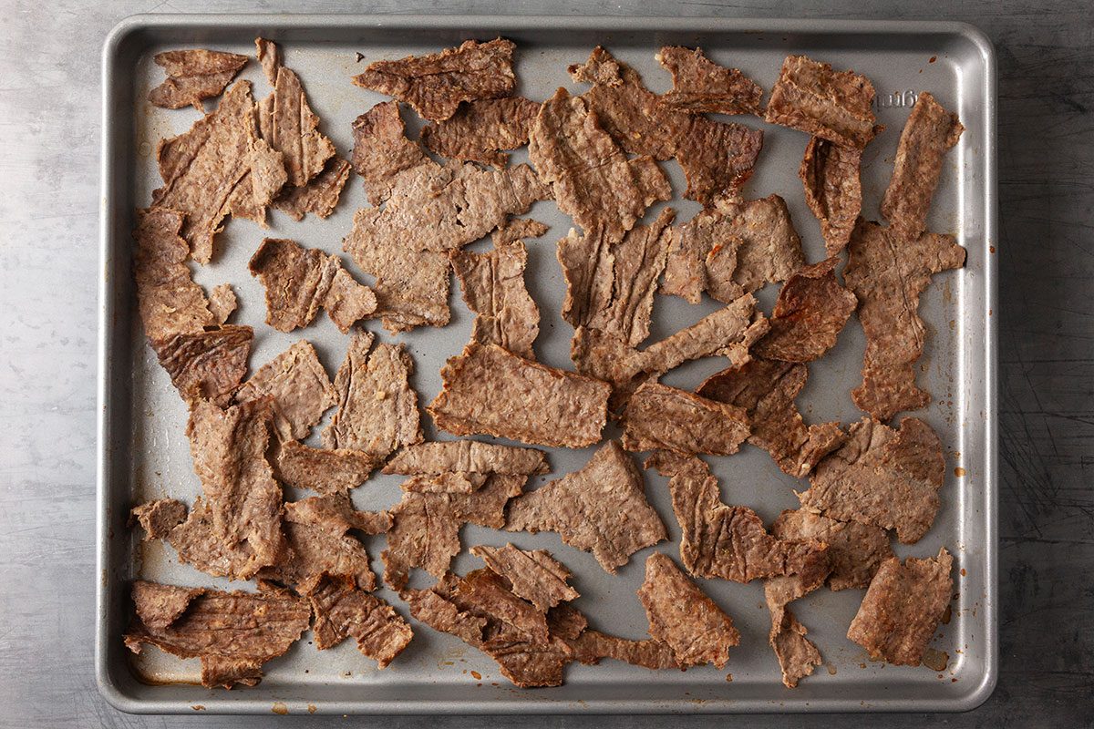 Overhead image of sliced gyro meat spread across a sheet pan after baking, showing crisped edges and tender interior pieces.