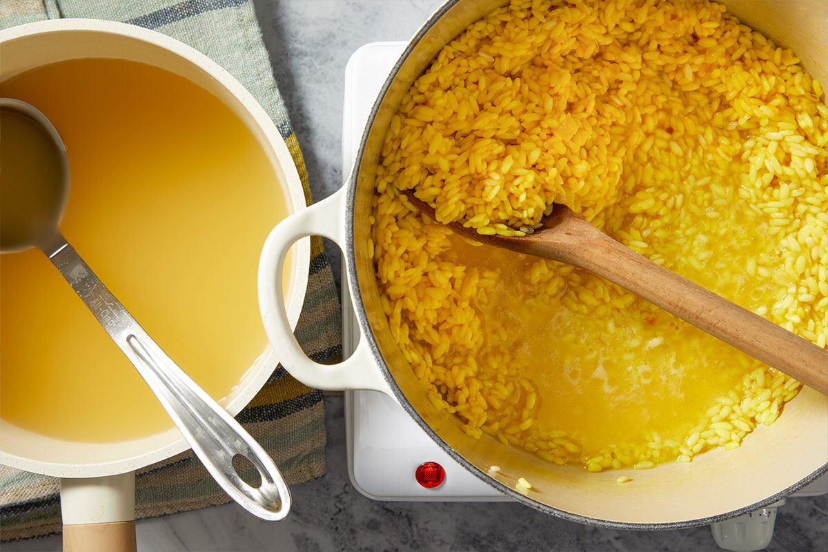 Overhead step-by-step image showing saffron risotto thickening in a Dutch oven while additional broth is stirred into the rice during cooking.