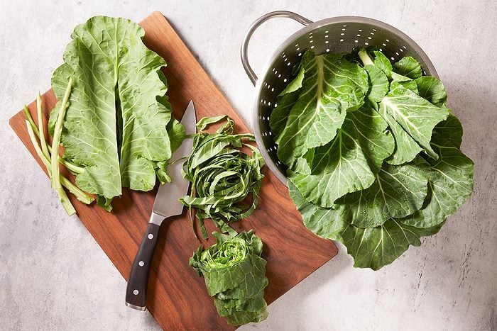 Stacking and rolling up washed collard leaves to cut them into thick strips.