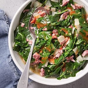 Slow Cooker Collard Greens in a bowl of white color with a spoon.