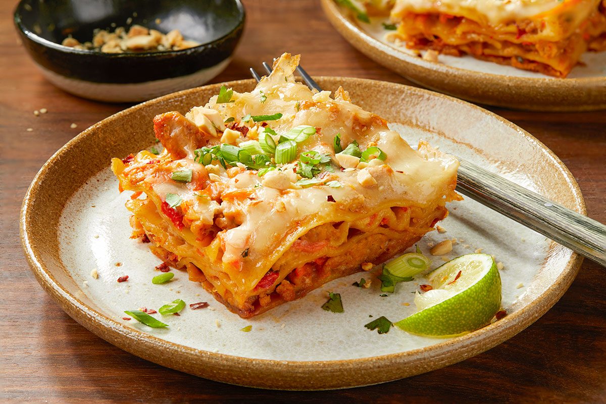 Eye-level vertical image of a plated slice of Thai-inspired turkey lasagna garnished with herbs and lime.