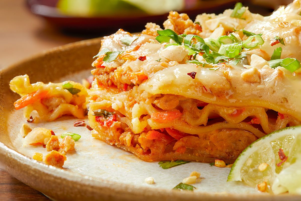 Eye-level horizontal close-up of Thai-inspired turkey lasagna showing layered noodles, sauce, and garnishes.