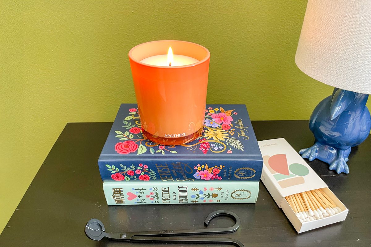 home-made candle on books next to a lamp and box of matches