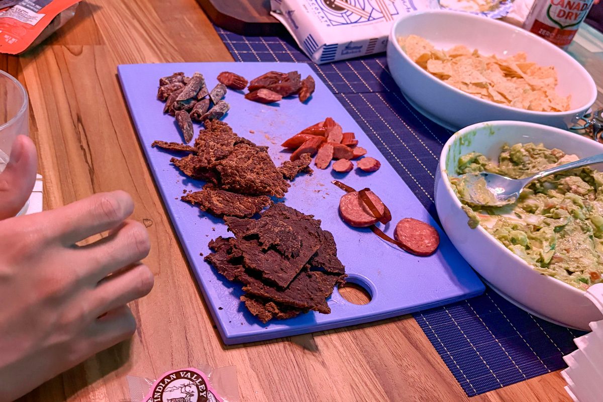 different jerky flavors on a board next to bowls of food
