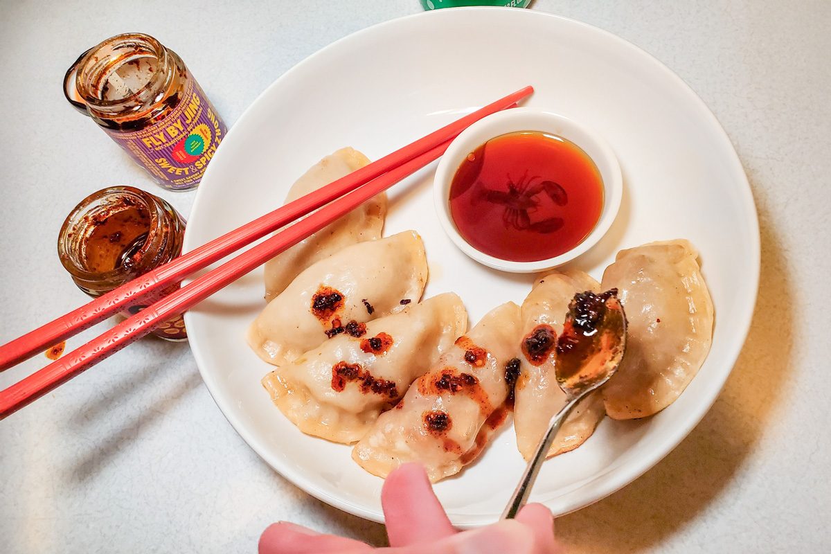 home-cooked dumplings on a plate with dipping sauce in a bowl next to two small glass jars