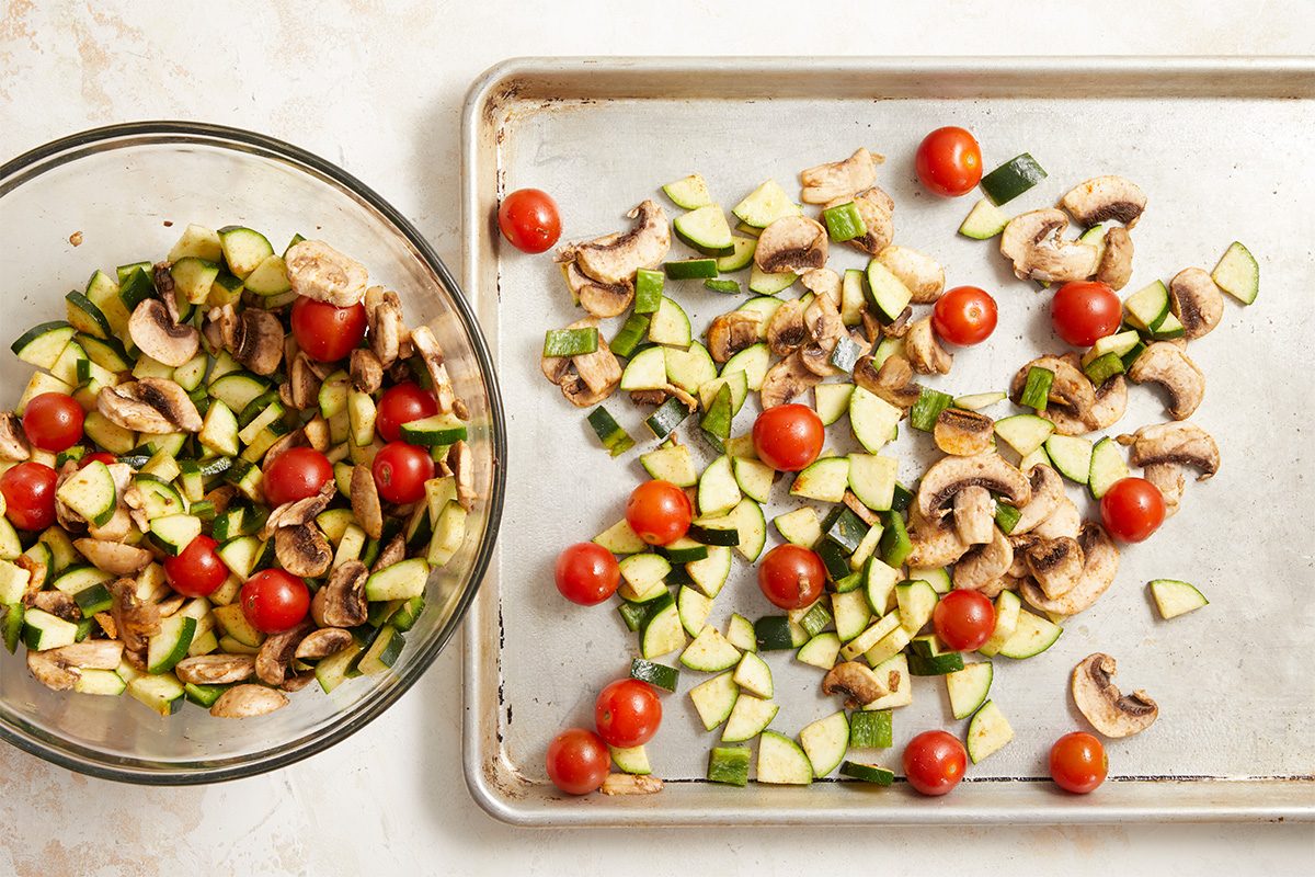 Overhead, horizontal step-by-step image showing fresh farmers market vegetables prepared for enchilada filling. Zucchini, poblano pepper, mushrooms, and cherry tomatoes are chopped and tossed together, emphasizing freshness and color. This Fast Track instructional image illustrates early prep for Farmers Market Enchiladas, highlighting wholesome ingredients and clean kitchen workflow for print and digital recipe content.