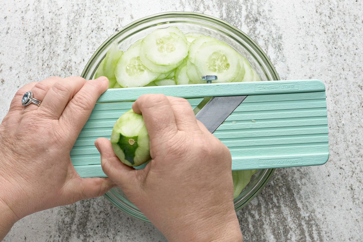 slicing cucumbers over a bowl
