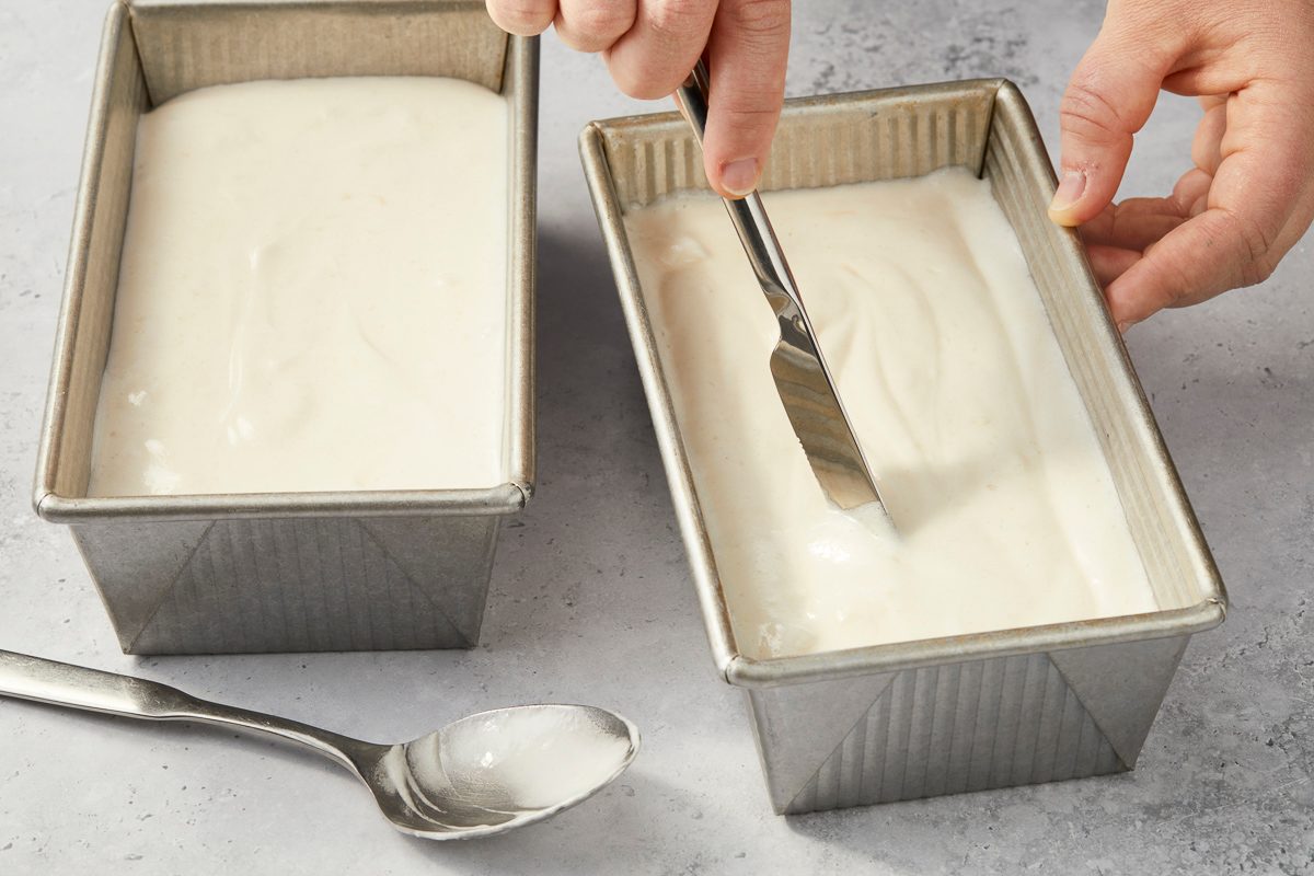 Using a butter knife to cut through the batter in loaf pan to remove air pockets