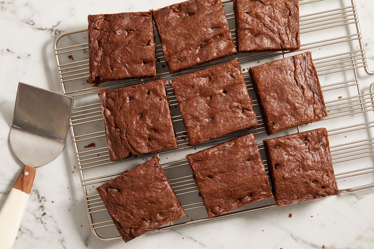Overhead horizontal image of baked avocado brownies cut into squares and cooling on a rack.