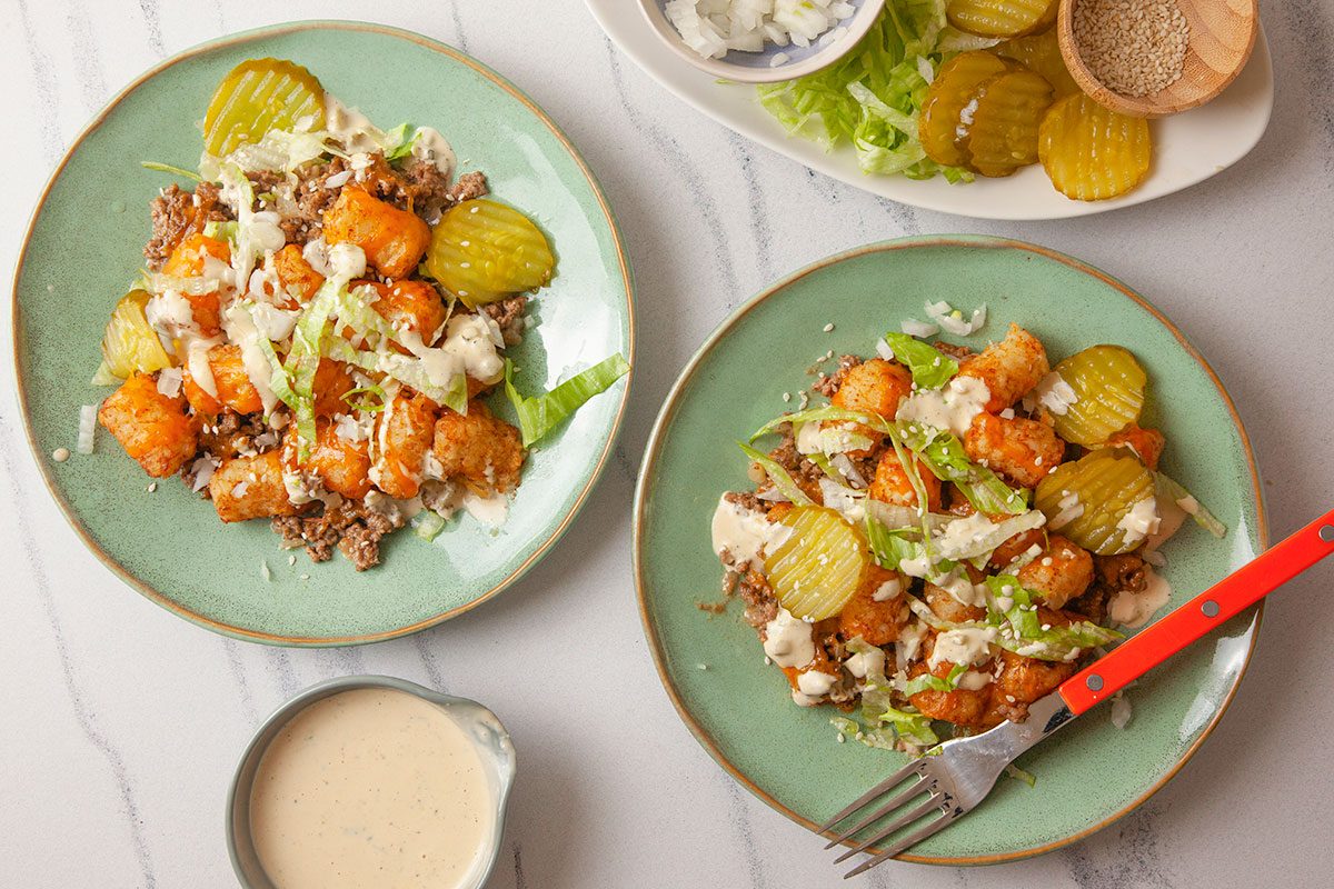 Big Mac casserole is plated and topped with shredded lettuce, pickles, and sauce for serving.