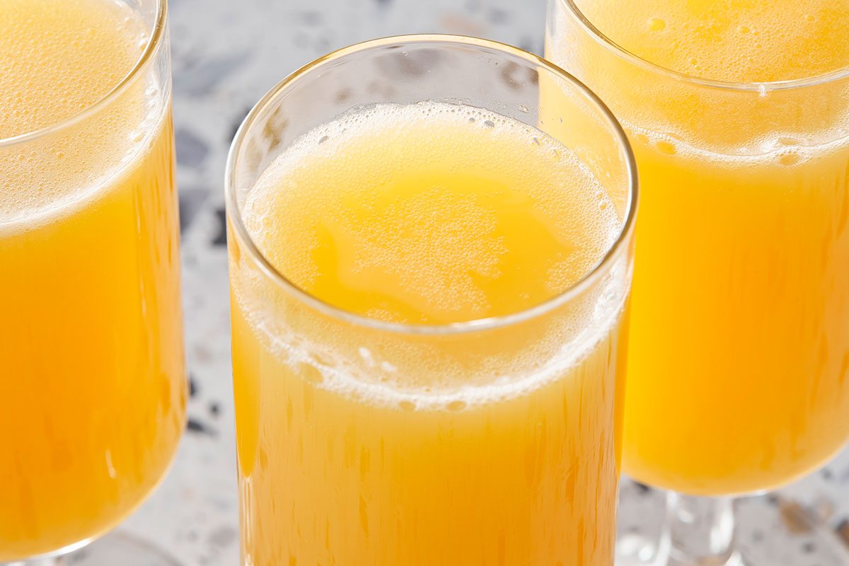 A horizontal close-up shows the surface of a mimosa with bubbles and condensation on the glass.