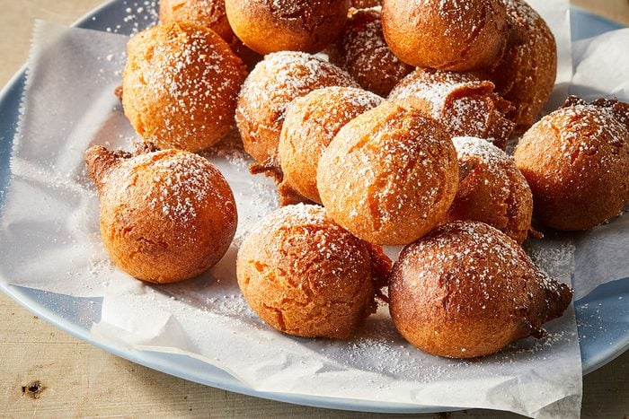 Eye-level horizontal image of a plate of freshly fried beignets coated in powdered sugar