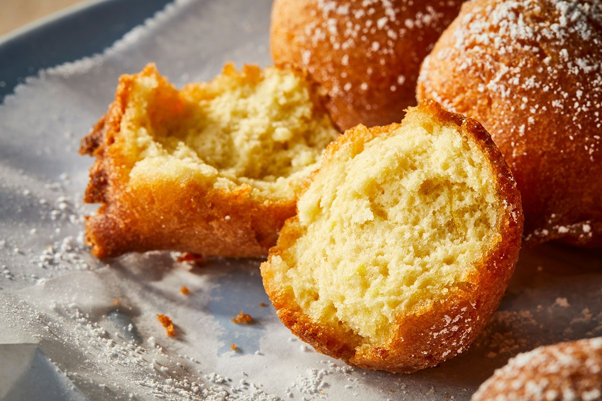 Close-up horizontal image of a split beignet revealing a soft airy interior