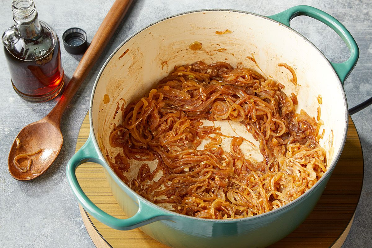 Overhead horizontal image of caramelized onions cooking in a Dutch oven, showing deep golden color and texture. Sprinkle roast with half the salt and pepper. In a Dutch oven, heat oil over medium heat. Brown roast on all sides. Remove from pan to a 6-qt. slow cooker. Add onion and remaining 1/2 teaspoons of salt and pepper to the same pan; cook and stir until tender, 5-7 minutes. Reduce heat to medium-low. Cook 20-25 minutes, stirring every 5 minutes, until onions are a golden brown color. Add garlic and maple syrup; cook and stir 5 minutes longer.