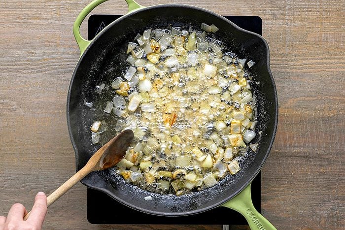 onions being cooked in a large skillet with butter and bacon fat