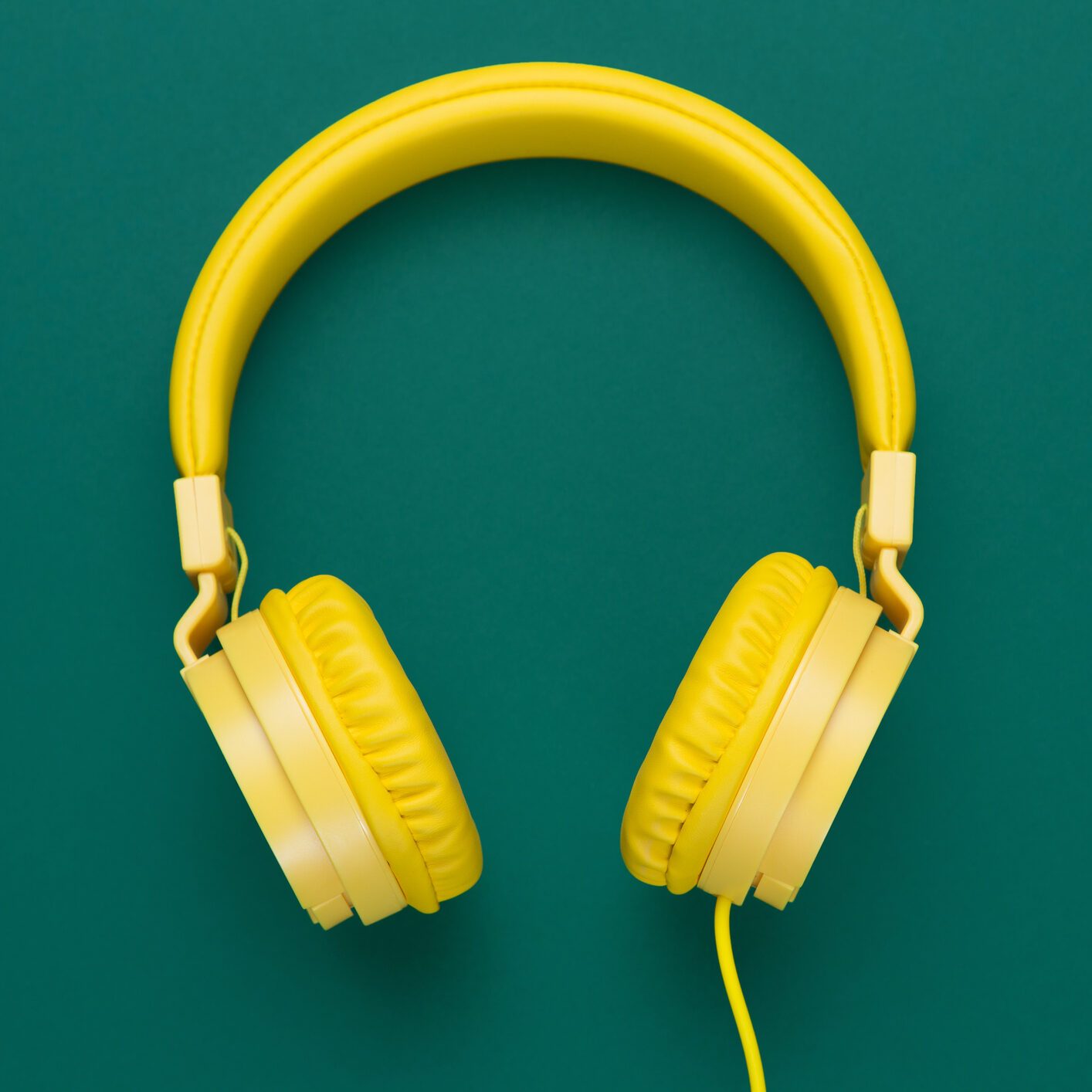 Yellow headphones on green background. Music concept.