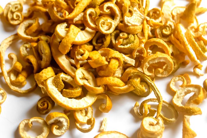Dried citrus fruit skin. Dry citrus skin for tea and compote. Dried skin of sweetie. the skin of the lemon is cut and dried. on a white background lies a mountain of dried mandarin skin.