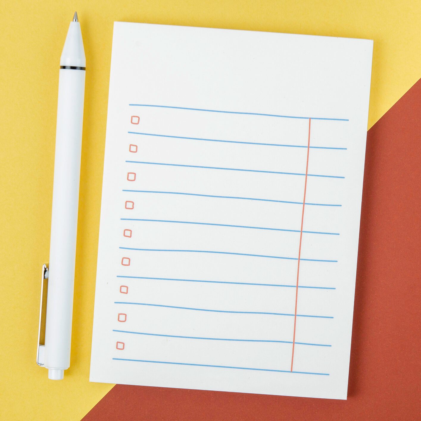 Blank lined notepad and white pen against a two-tone background.