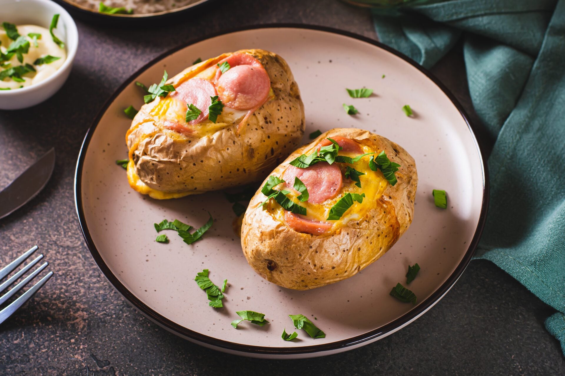 Baked potatoes in skins with egg and pieces of sausage on a plate on the table