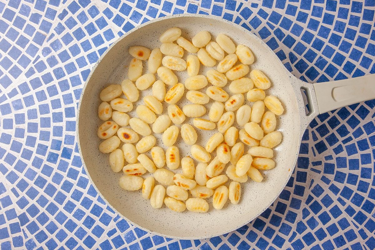Potato gnocchi are sautéed in a skillet until lightly golden and crisp on the outside.