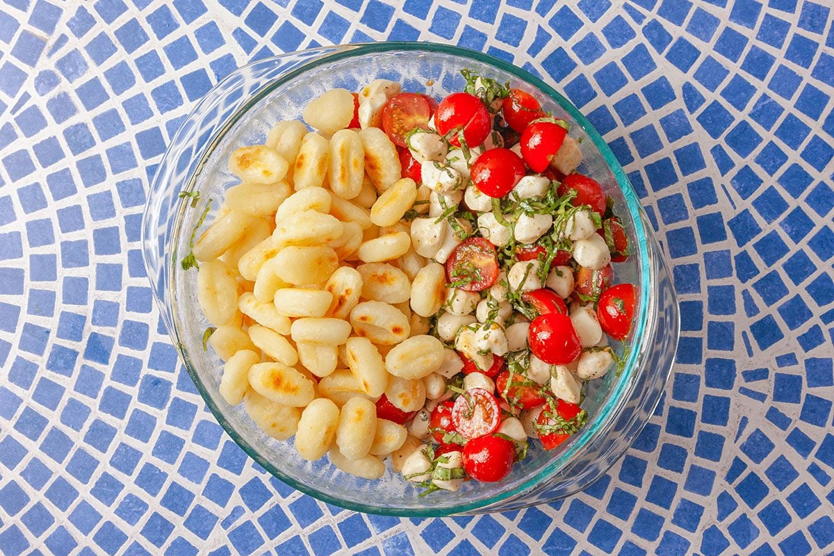 Crispy gnocchi are added to the bowl with tomatoes, mozzarella, and basil to assemble the salad.