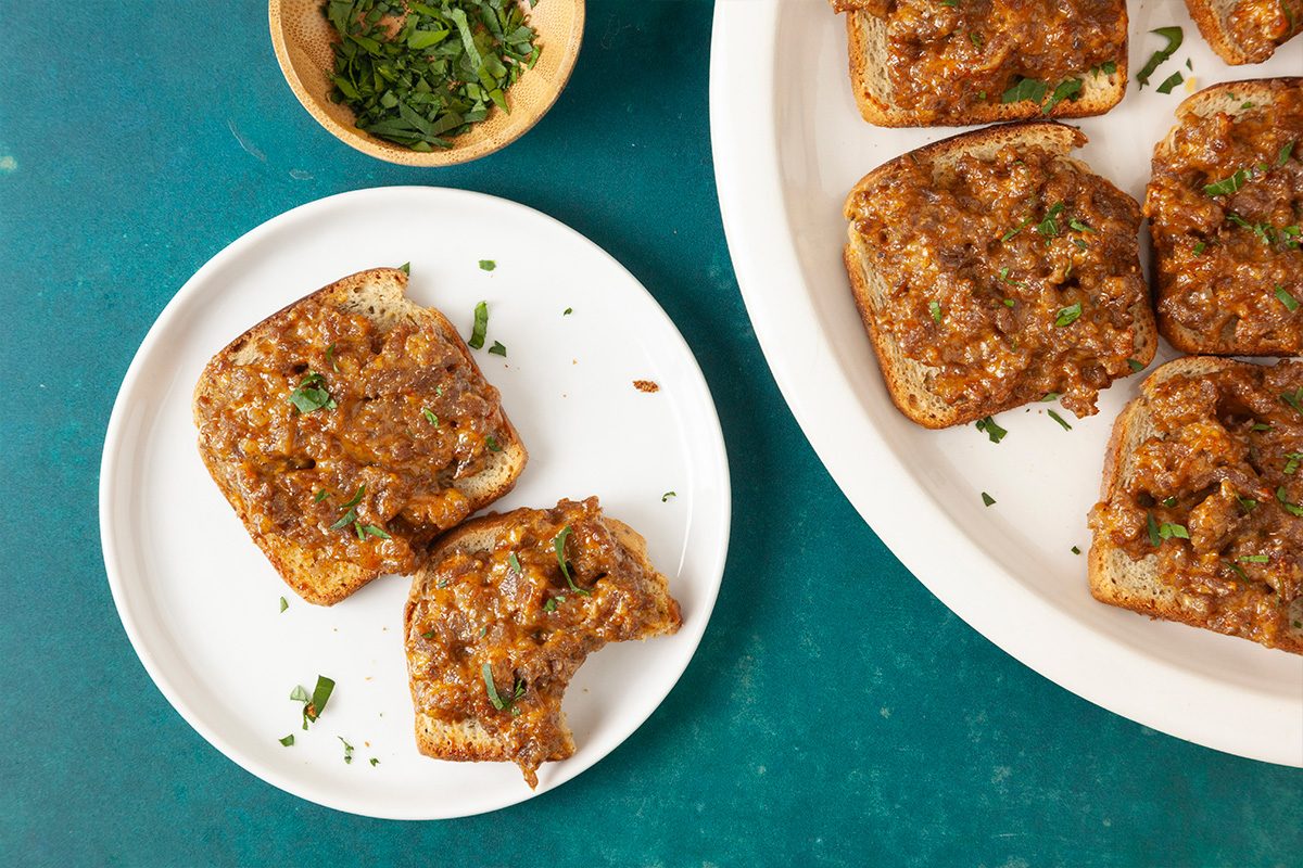 3/4 angle horizontal image of rye melt appetizers on a plate showing texture and topping detail.