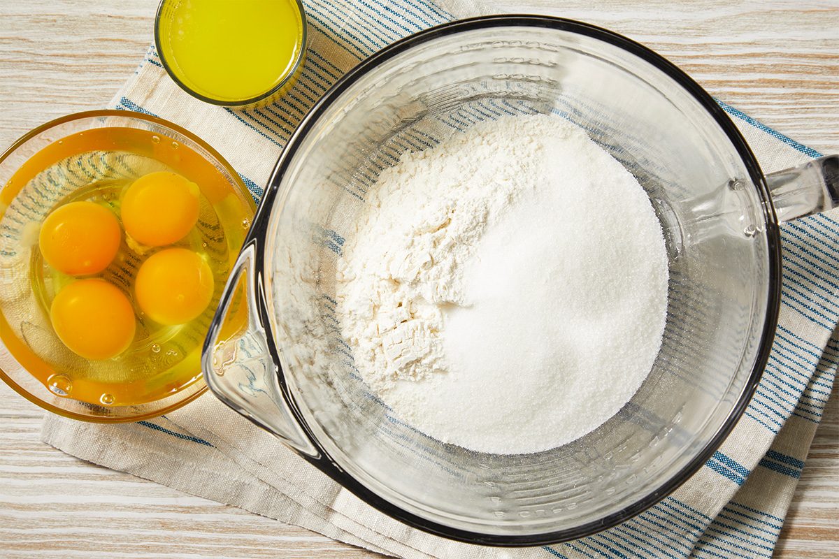 Overhead horizontal image of dry ingredients and eggs prepared in a mixing bowl for Impossible Pie.