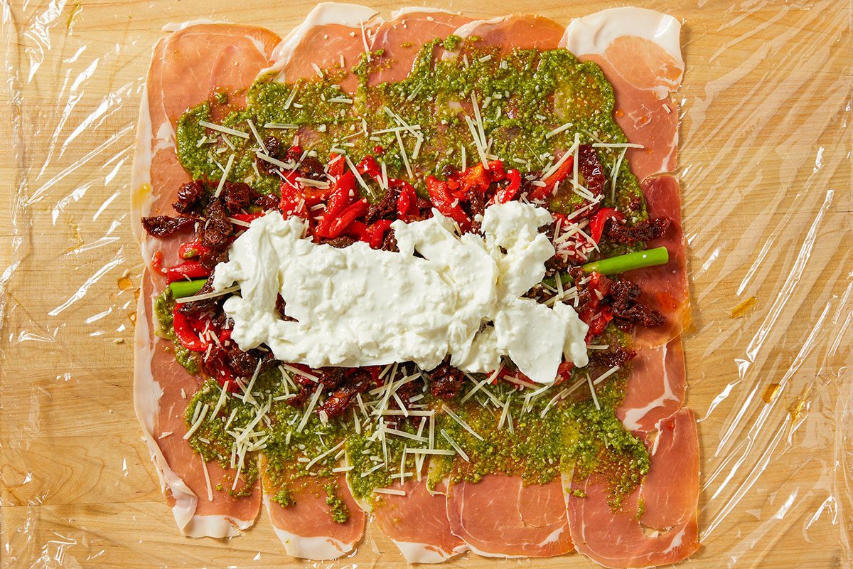 Burrata, roasted red peppers, sun-dried tomatoes, and Parmesan are layered over the pesto base.